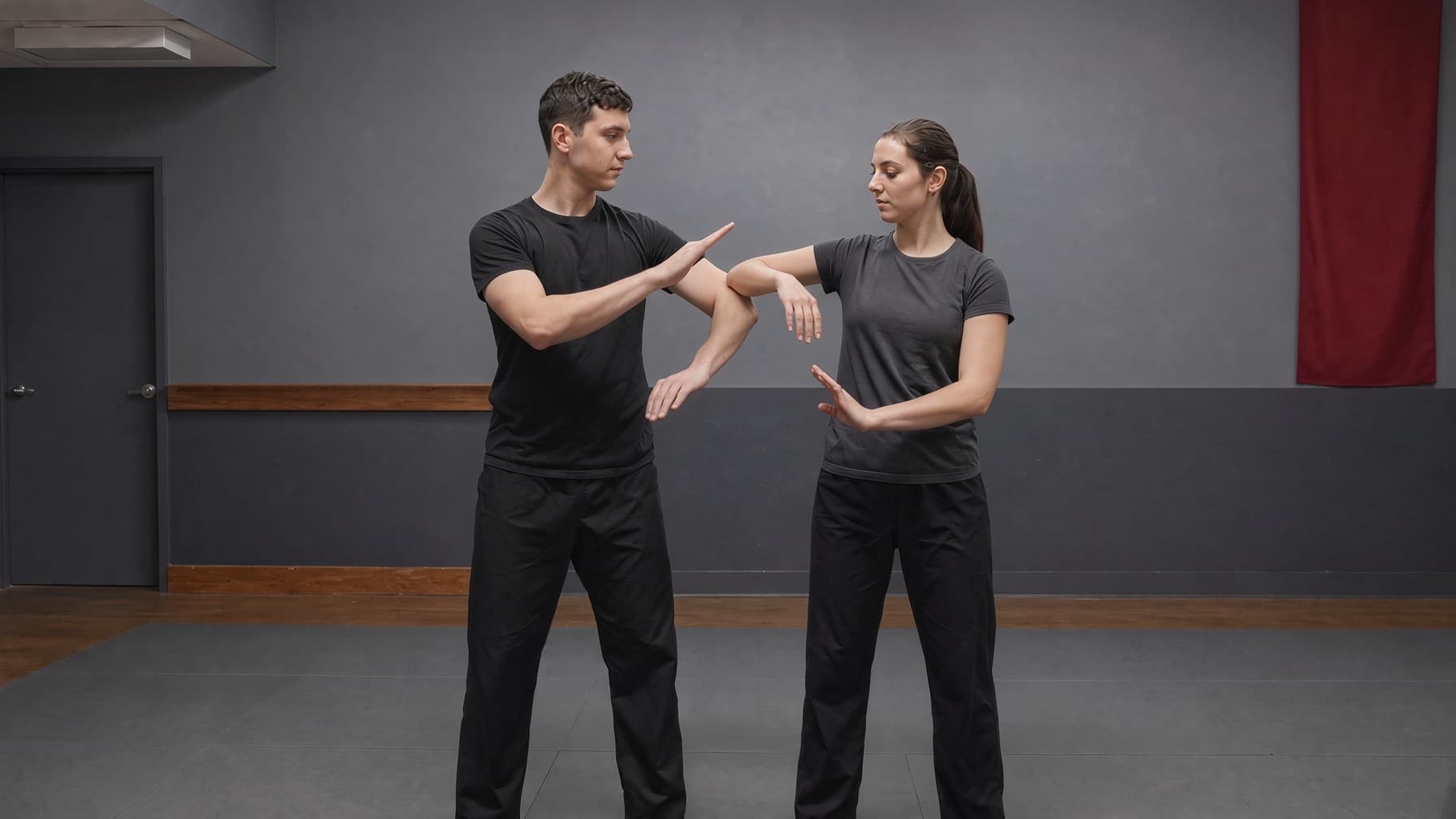 Two adults practicing calm close-range Wing Chun sticky hands in a training hall